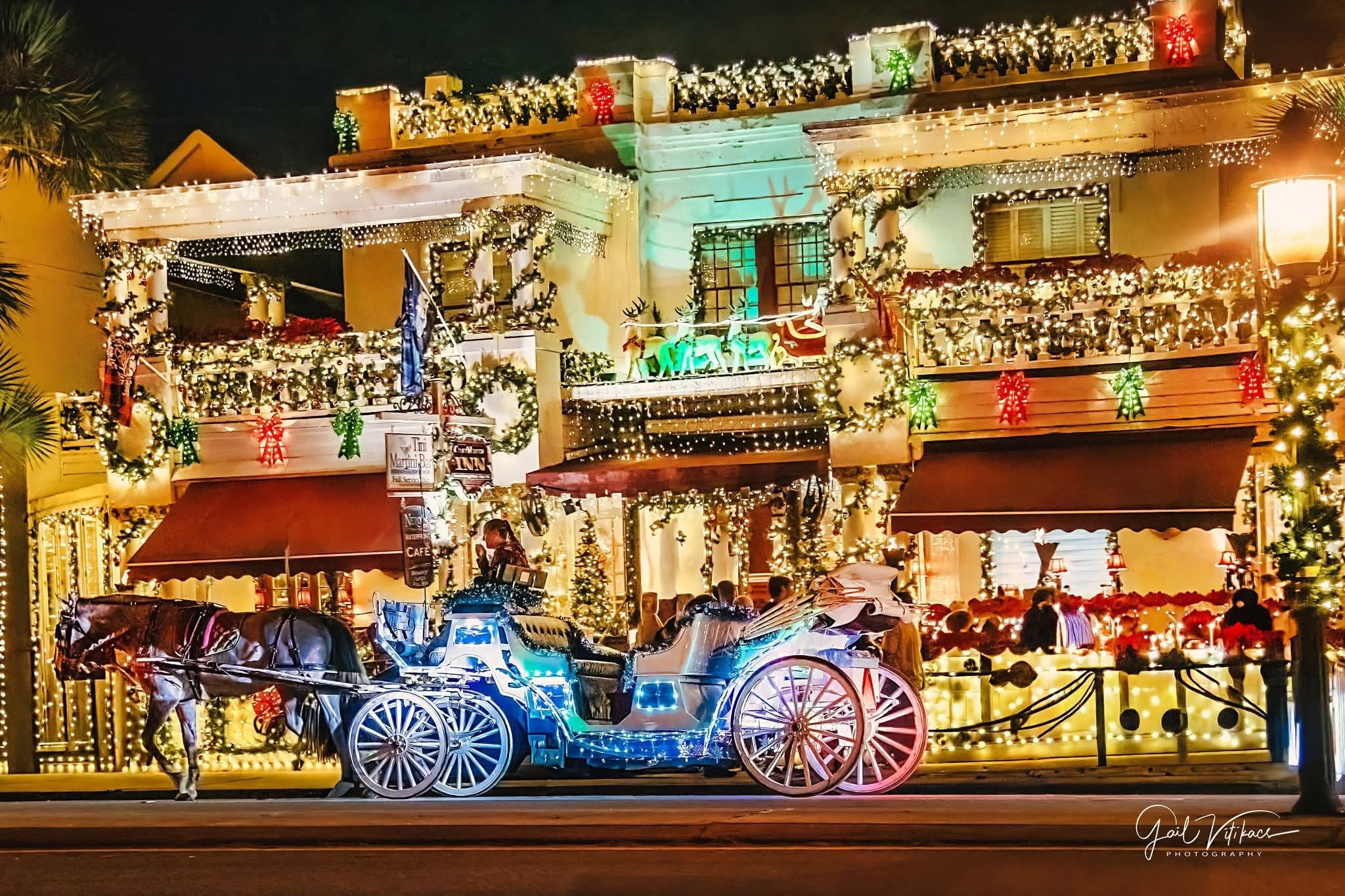 A decorated carriage in front of a building covered in holiday lights.